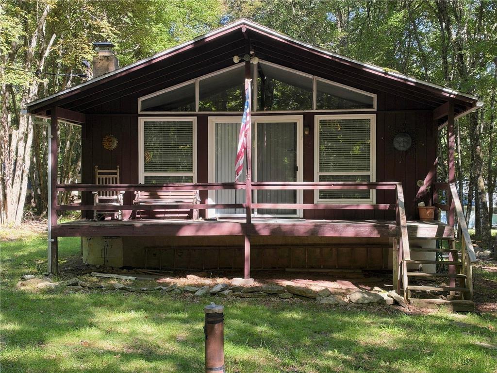 116 Aspen Road Albrightsville, PA 18210 - Photo 2 of 33 Wooded surroundings frame a classic rustic cabin featuring a spacious front deck and expansive windows.