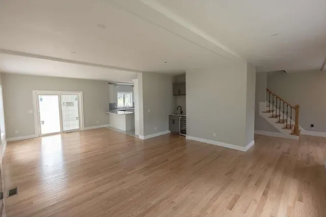 a view of an empty room with window and wooden floor