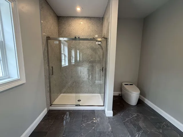 a bathroom with a granite countertop toilet and a shower