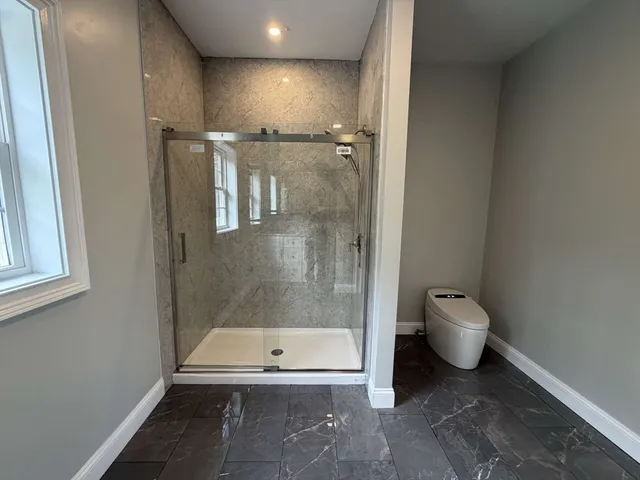 a bathroom with a granite countertop toilet and a shower
