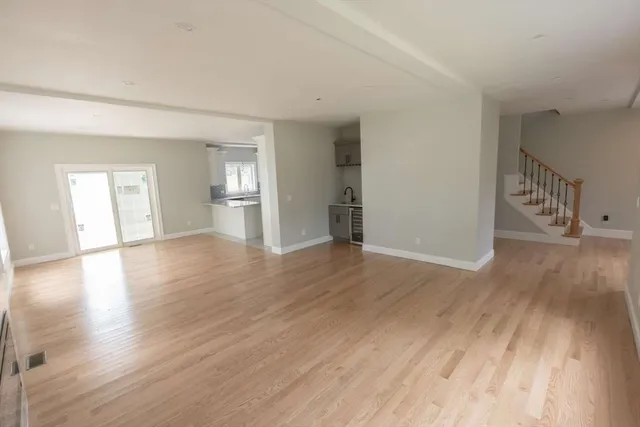 a view of empty room with wooden floor and kitchen