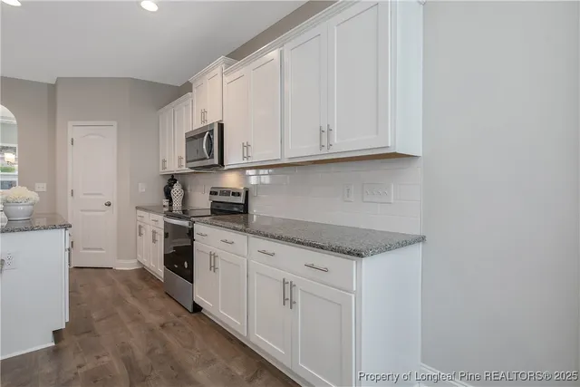 a kitchen with stainless steel appliances granite countertop a sink and dishwasher a stove top oven with white cabinets