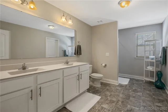 a spacious bathroom with a granite countertop sink toilet and a mirror