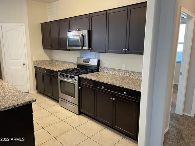 a kitchen with granite countertop a stove top oven microwave and cabinets