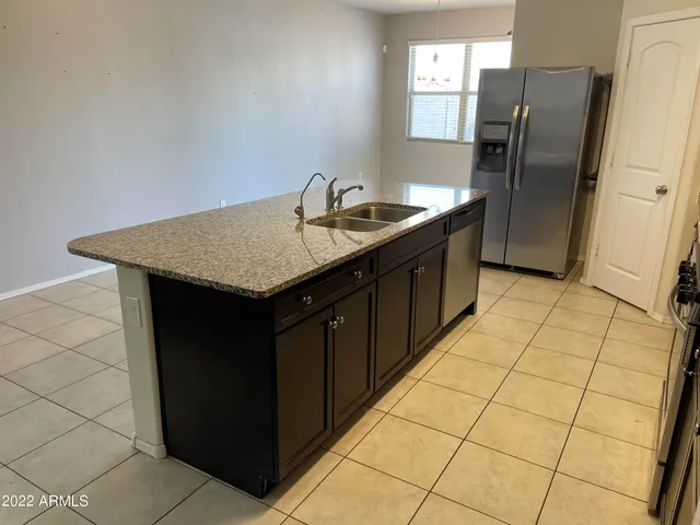a kitchen with a sink a refrigerator and wooden cabinets
