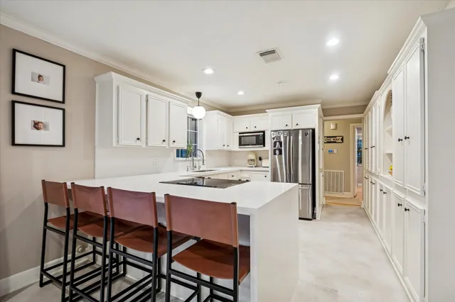 a kitchen with stainless steel appliances a refrigerator a stove a sink dishwasher and a dining table with wooden floor