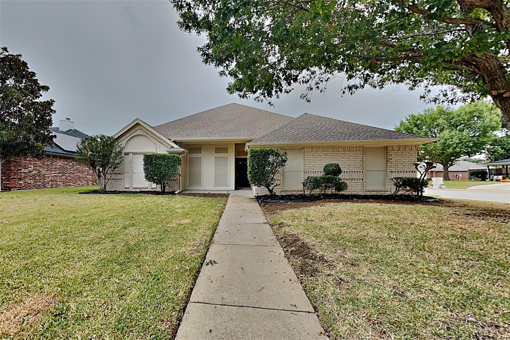 Single story home with a front yard, brick siding, and roof with shingles