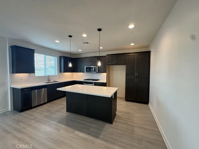 a large kitchen with a large counter top a sink stainless steel appliances and cabinets