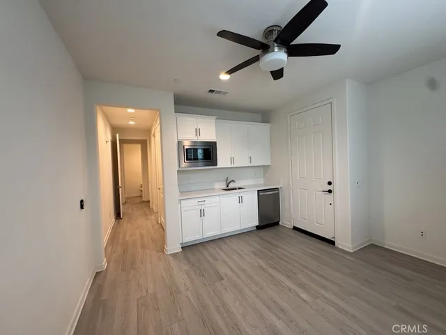 a large kitchen with a wooden floor and white stainless steel appliances