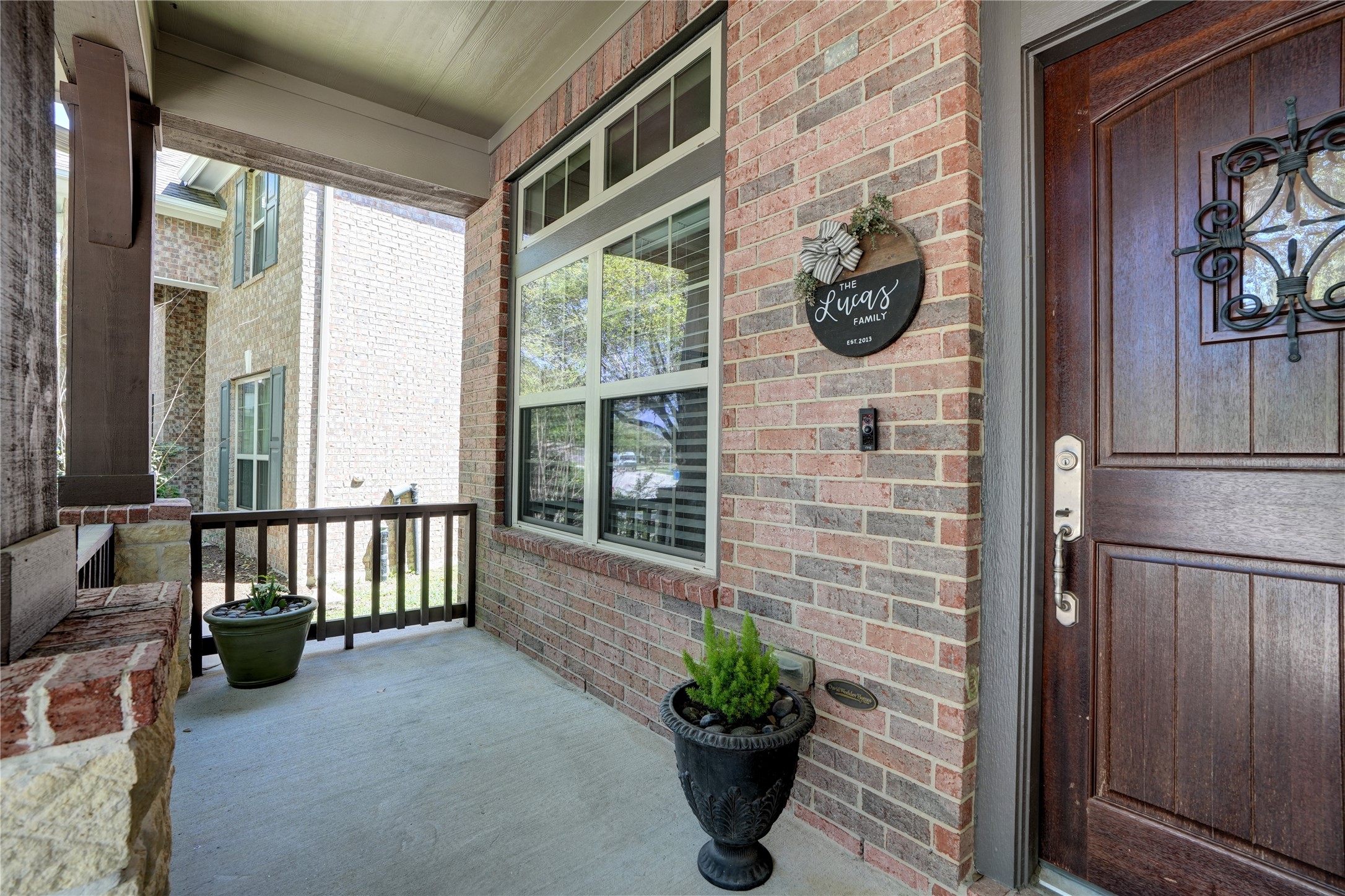 27243 Jessica Hills Lane Spring, TX 77386 - Photo 6 of 49 Charming single-story home with a welcoming front porch, nestled among mature trees.This inviting front porch features a charming brick exterior, a wooden door with decorative ironwork, and space for potted plants. Perfect for welcoming guests.