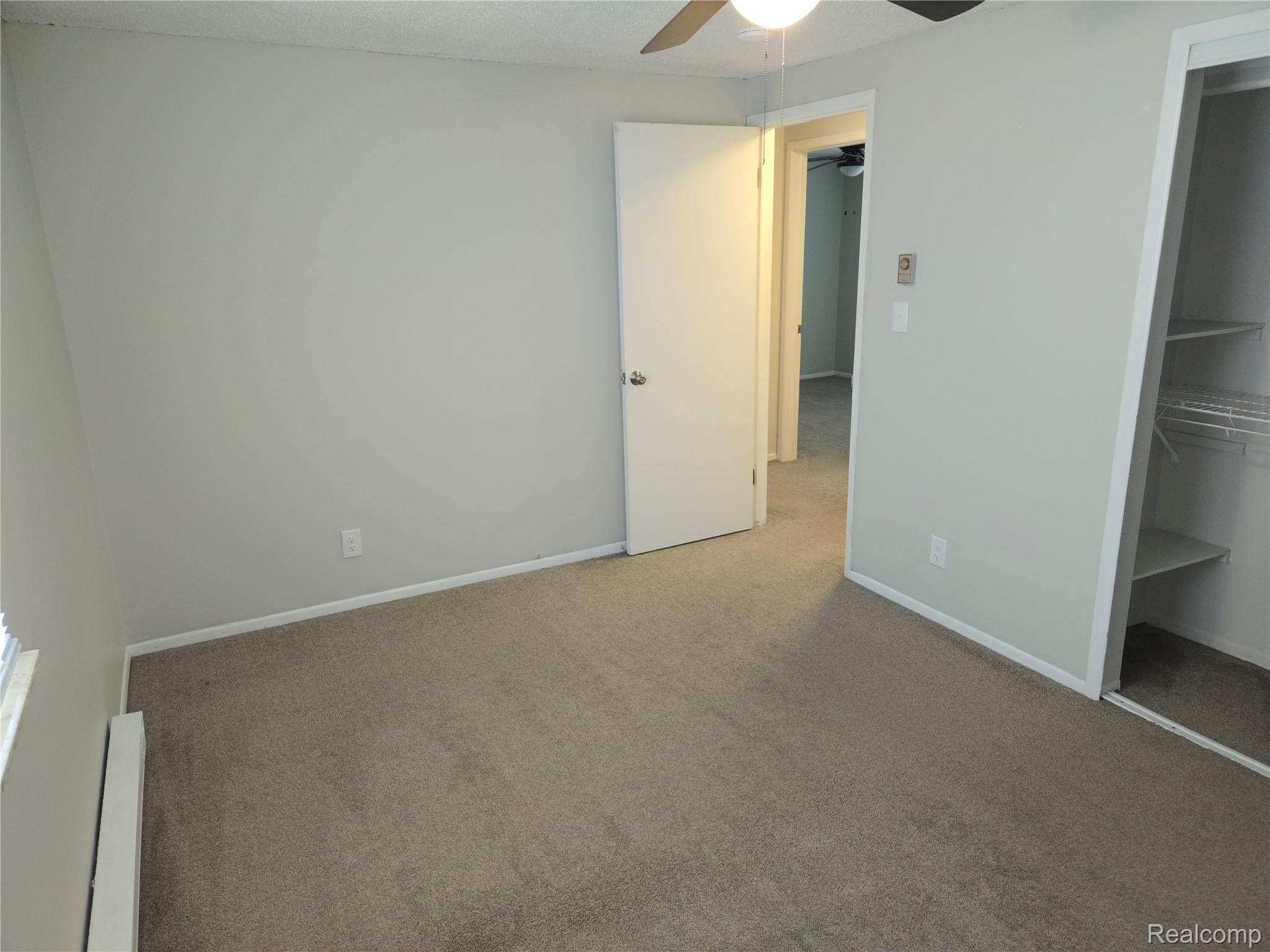27780 Reo Road Grosse Ile, MI 48138 - Photo 12 of 18 Carpeted room featuring light gray walls, white trim, a ceiling fan with integrated lighting, and a closet with built-in shelving