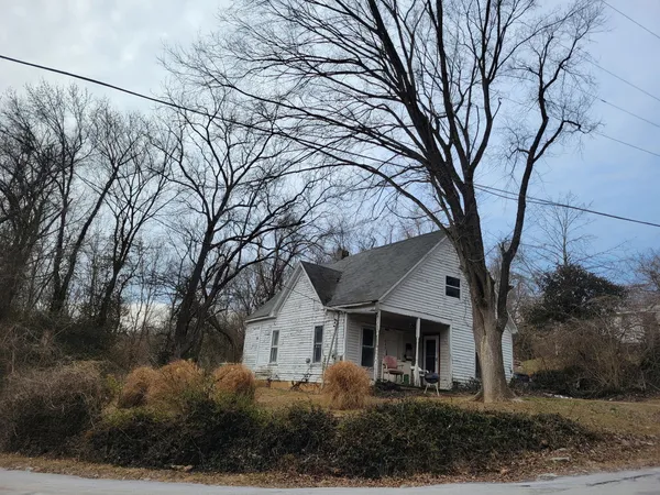a front view of a house with trees and plants