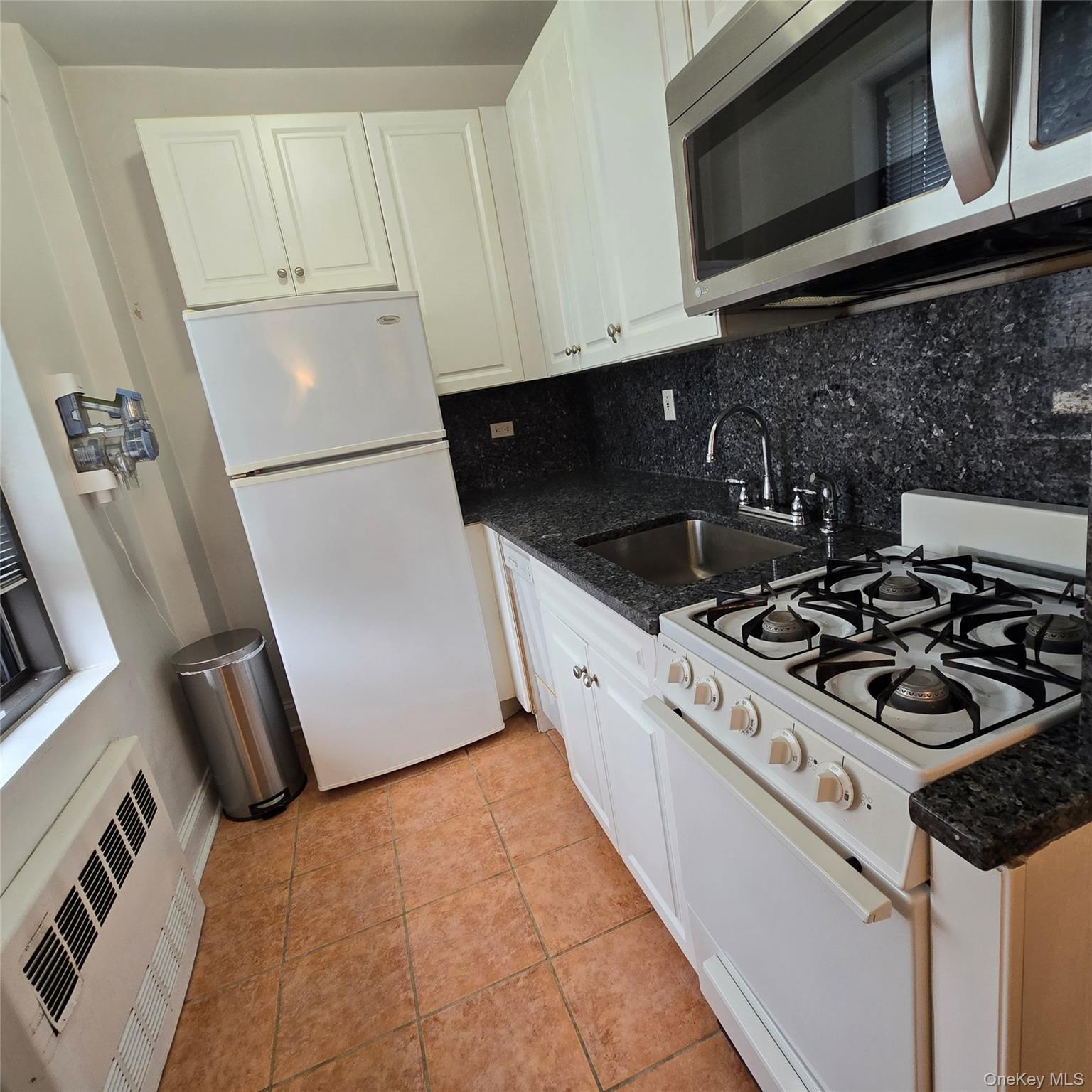 99-40 63rd Road, Unit 1O Queens, NY 11374 - Photo 8 of 14 a kitchen with a stove a microwave and refrigerator