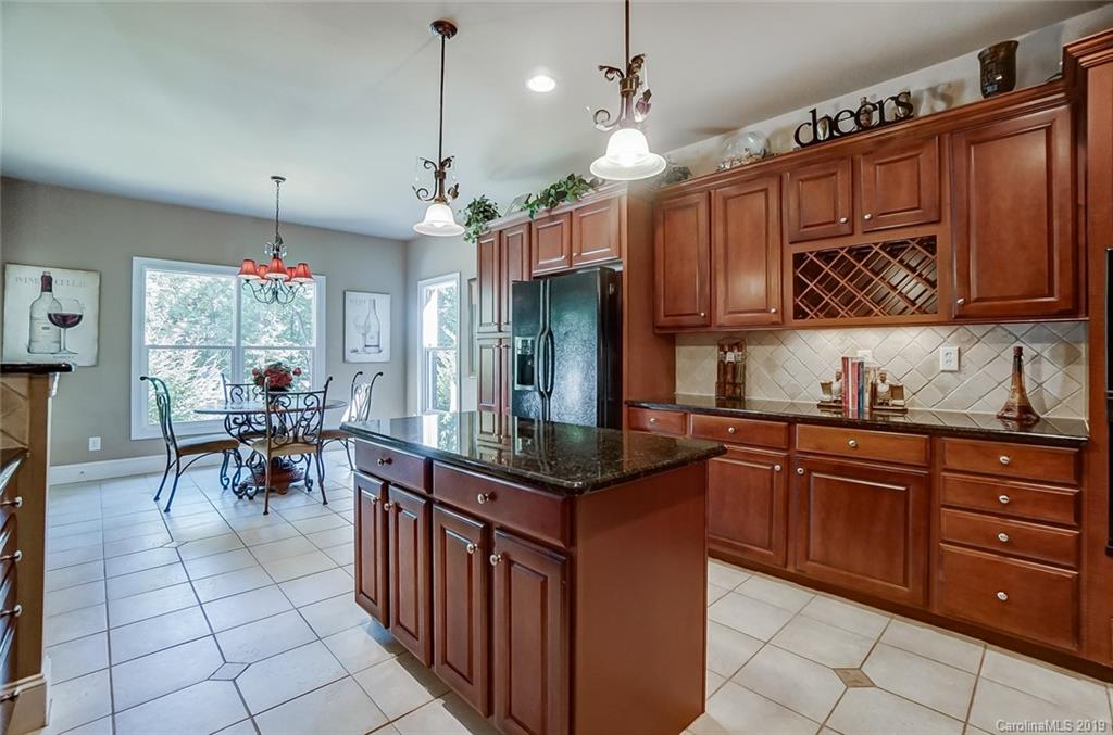 421 Greenbay Road Mooresville, NC 28117 - Photo 10 of 25 a kitchen with granite countertop a stove a sink dishwasher a dining table and chairs with wooden floor