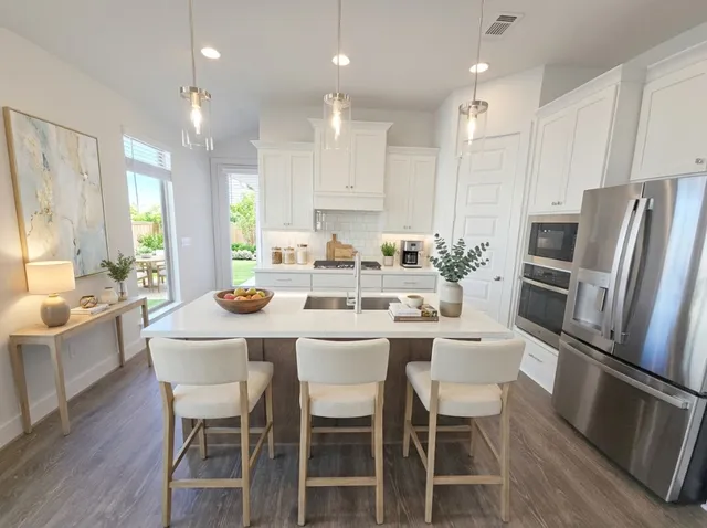 a dining room with stainless steel appliances kitchen island granite countertop a dining table chairs and a refrigerator