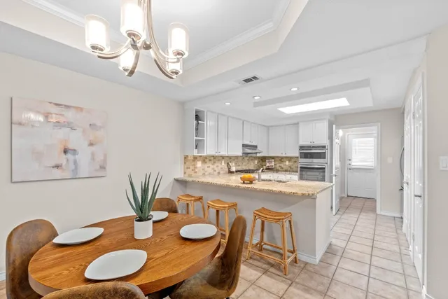 a kitchen with stainless steel appliances granite countertop a dining table chairs and white cabinets