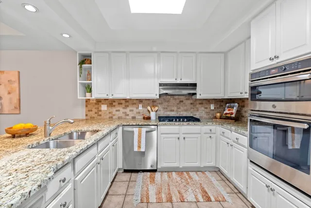 a kitchen with granite countertop a sink stove and cabinets