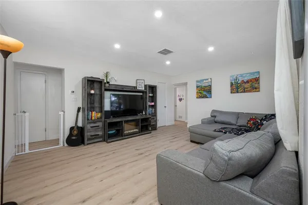 a living room with furniture a flat screen tv and a refrigerator