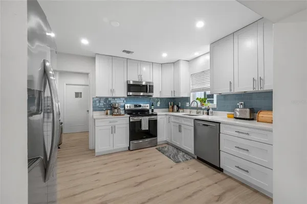 a kitchen with a refrigerator stove and white cabinets