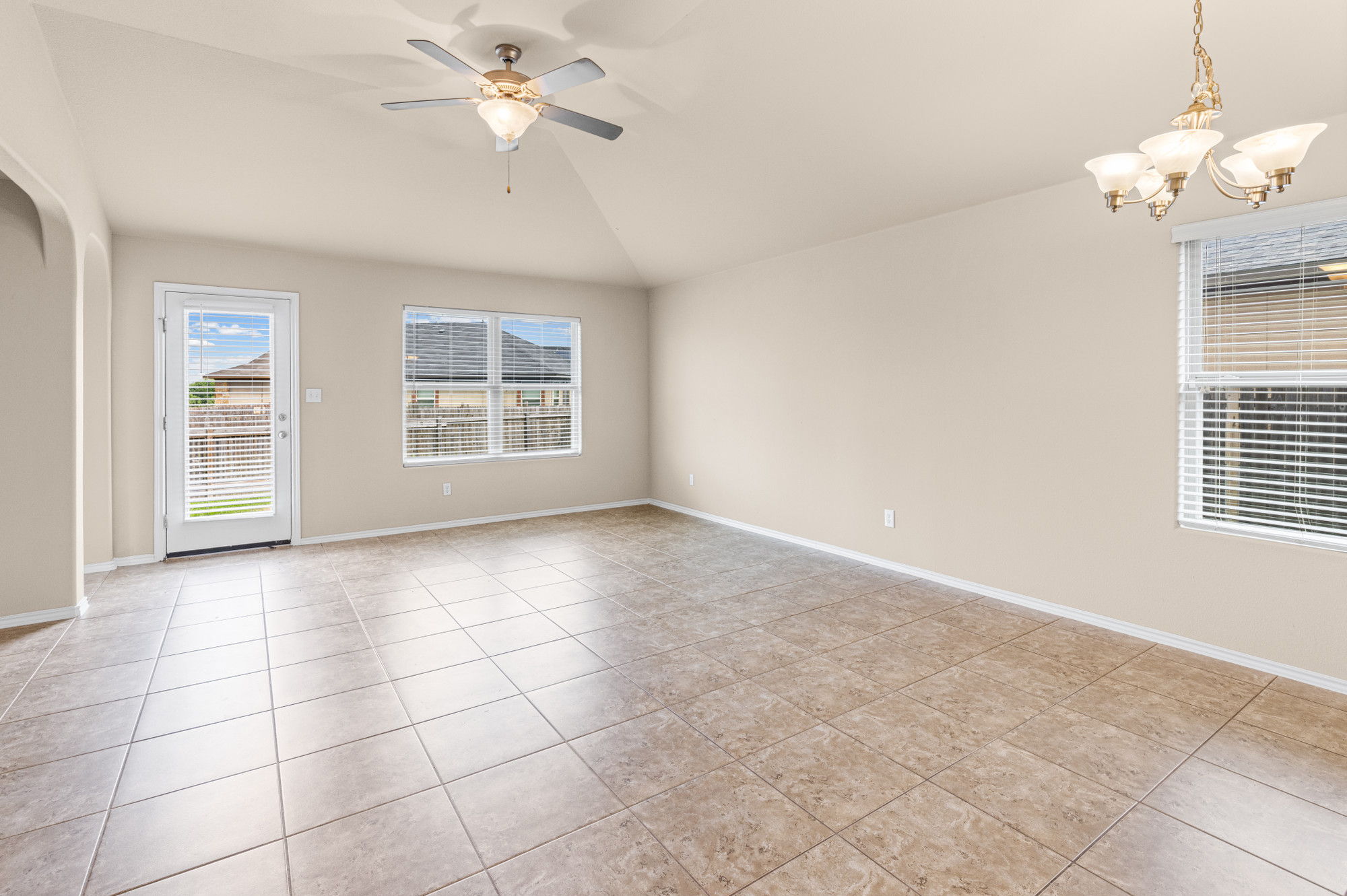 19308 Stokes Lane Pflugerville, TX 78660 - Photo 5 of 27 Spacious room featuring neutral-toned tile flooring, vaulted ceiling, and an arched doorway