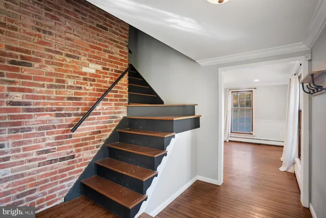 a view of an empty room with wooden floor fireplace and a window