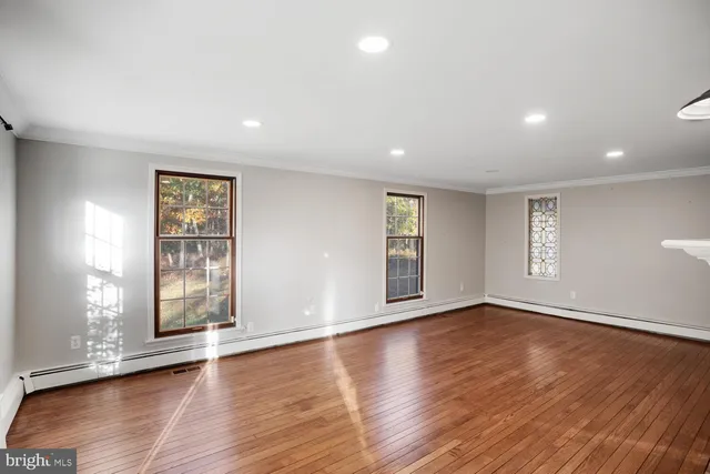 a view of an empty room with wooden floor fireplace and a window