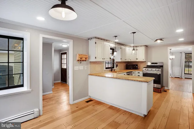 a kitchen with stainless steel appliances granite countertop a stove a refrigerator and a sink with wooden floor