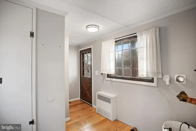 a view of empty room with wooden floor and window