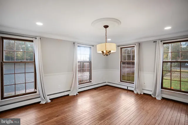 a view of a room with wooden floor chandelier and a kitchen space