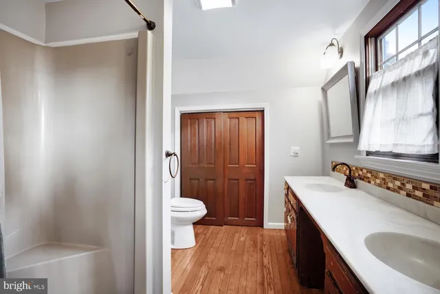 an empty room with wooden floor ceiling fan and windows