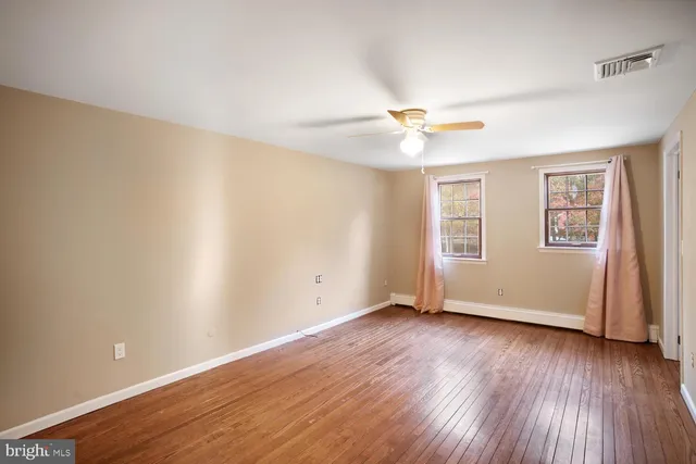 an empty room with wooden floor and a ceiling fan