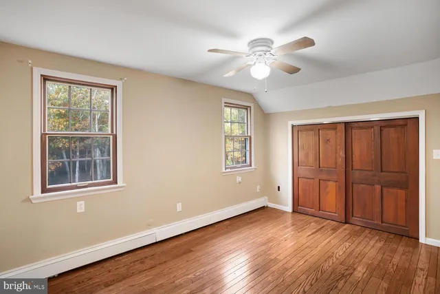 an empty room with wooden floor fan and windows