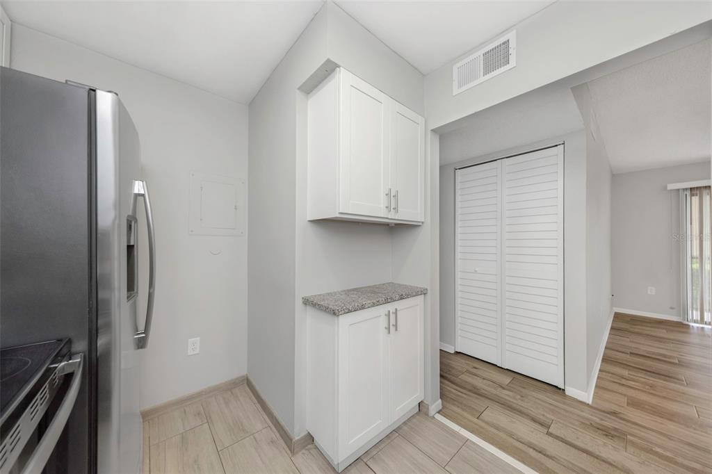 1308 Pine Ridge Circle East, Unit H1 Tarpon Springs, FL 34688 - Photo 30 of 50 a view of a kitchen with white cabinets and wooden floor