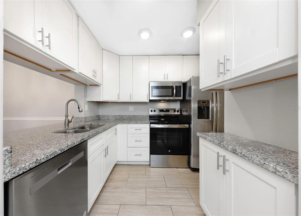 1308 Pine Ridge Circle East, Unit H1 Tarpon Springs, FL 34688 - Photo 5 of 50 a kitchen with stainless steel appliances granite countertop a sink stove and refrigerator