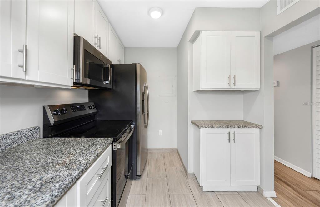 1308 Pine Ridge Circle East, Unit H1 Tarpon Springs, FL 34688 - Photo 7 of 50 a kitchen with stainless steel appliances granite countertop a stove microwave and sink