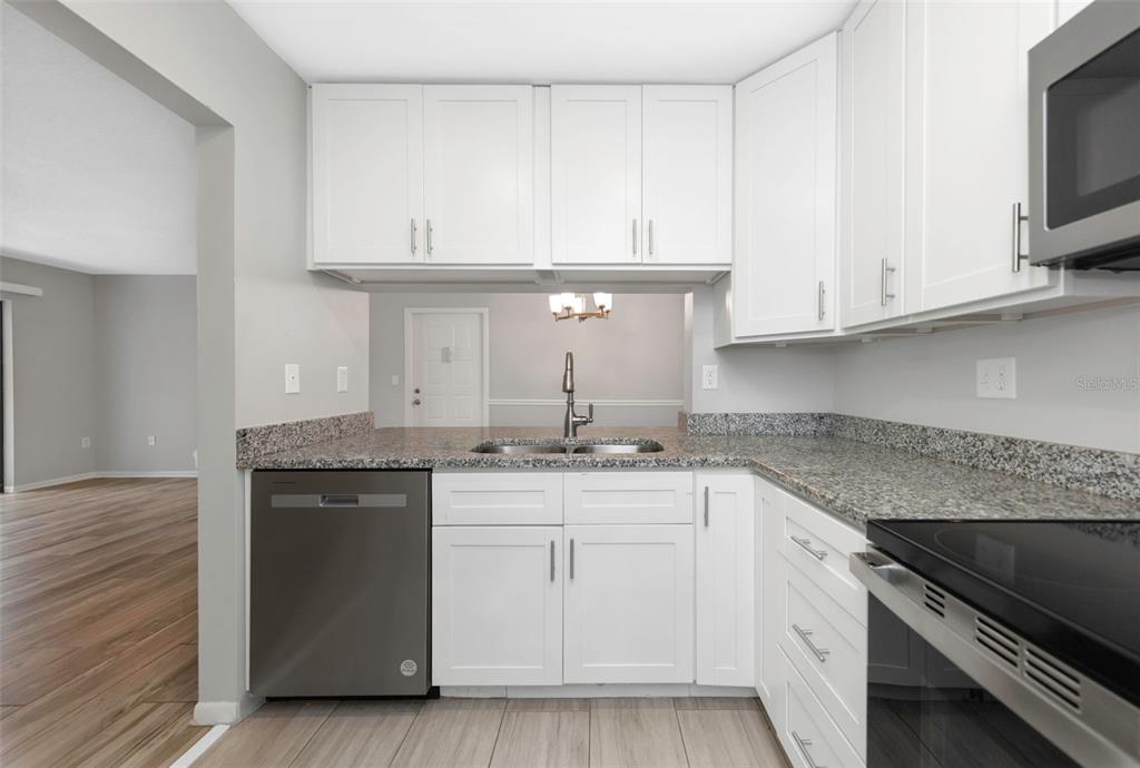 1308 Pine Ridge Circle East, Unit H1 Tarpon Springs, FL 34688 - Photo 8 of 50 a kitchen with stainless steel appliances granite countertop a sink and dishwasher a stove top oven with white countertops