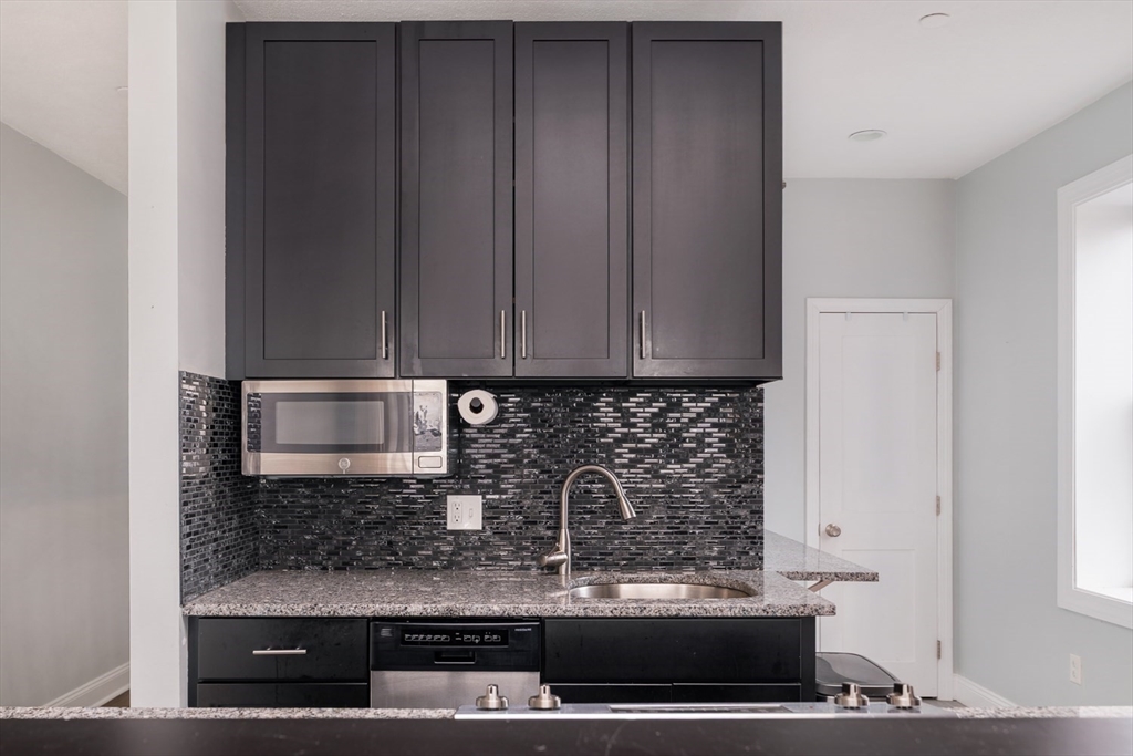 188 North Street, Unit 64 Boston, MA 02113 - Photo 13 of 27 a kitchen with granite countertop white cabinets and stainless steel appliances