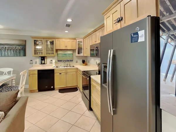 a kitchen with stainless steel appliances granite countertop a refrigerator a stove a sink and white cabinets with wooden floor