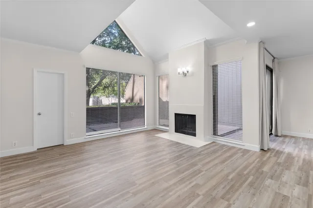 an empty room with wooden floor fireplace and windows