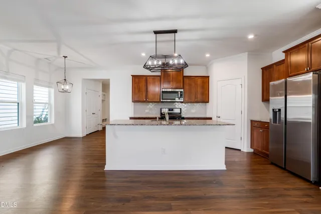 a large kitchen with stainless steel appliances granite countertop a sink dishwasher a microwave oven a stove with wooden floor and cabinets