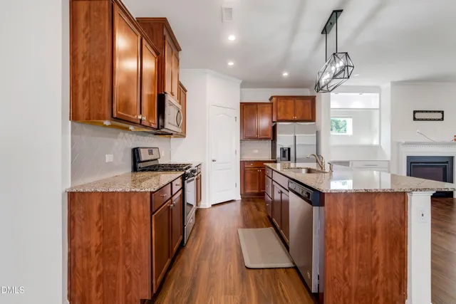 a kitchen with granite countertop stainless steel appliances wooden cabinets and a stove top oven