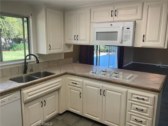 a kitchen with white cabinets and sink