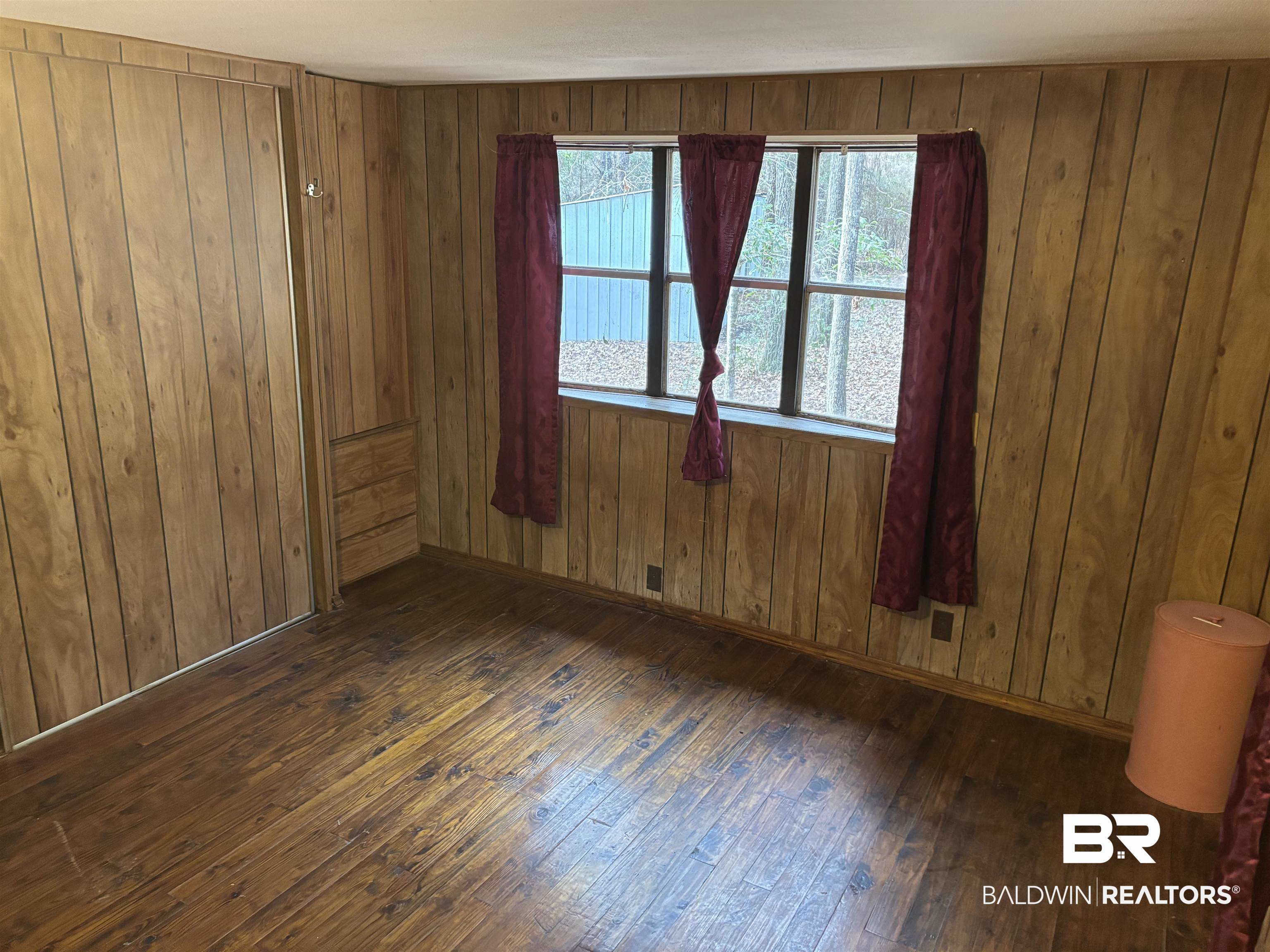 15575 Rogers Drive Chunchula, AL 36521 - Photo 36 of 42 Empty room with dark wood-style floors, wooden walls, and baseboards