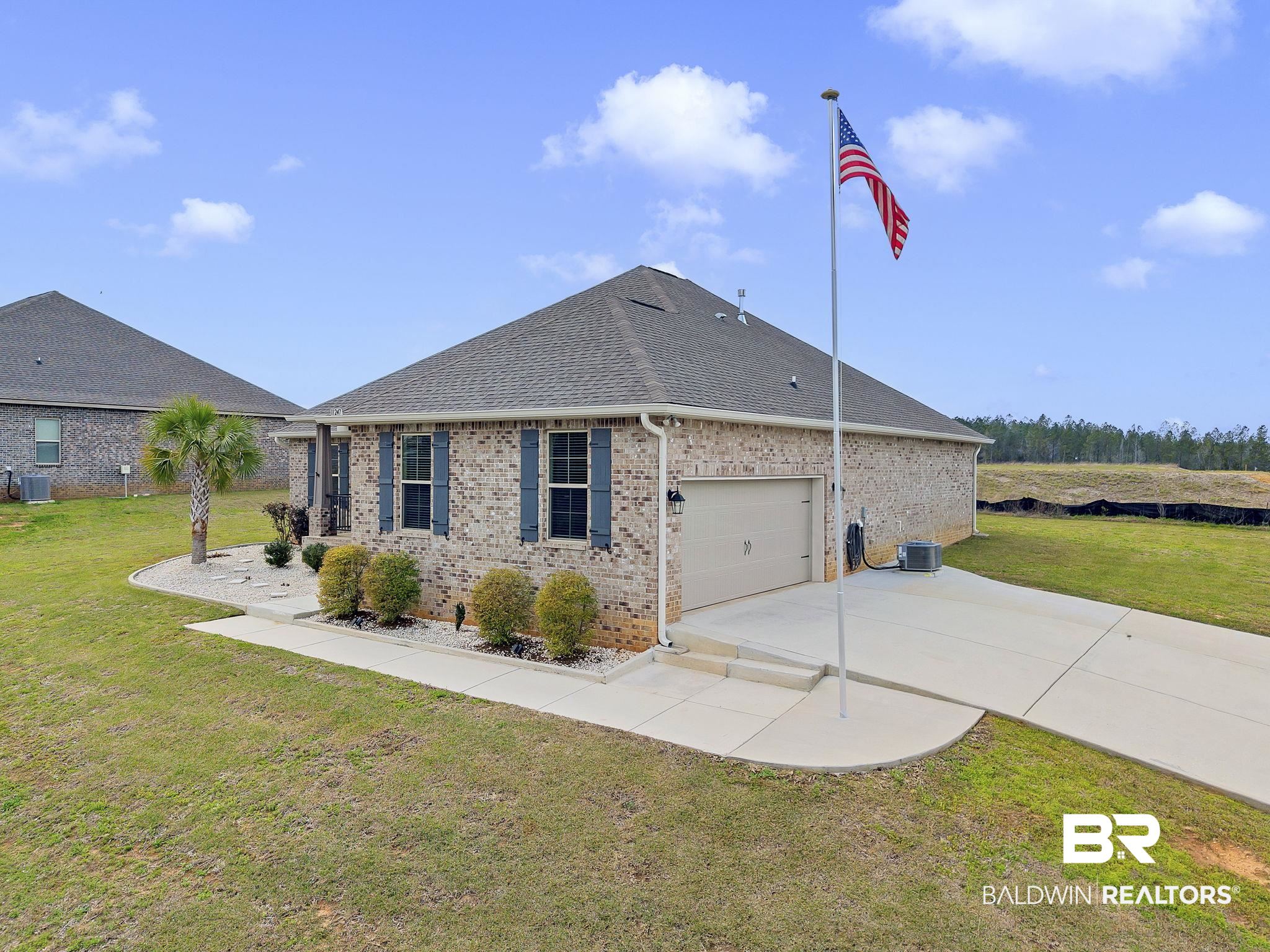 11247 Thistledown Loop Spanish Fort, AL 36527 - Photo 4 of 72 View of side of home featuring brick siding, a lawn, driveway, and roof with shingles