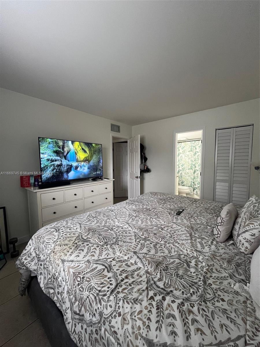 8075 Northwest 7th Street, Unit 109 Miami, FL 33126 - Photo 14 of 14 a bedroom with a bed and a flat screen tv