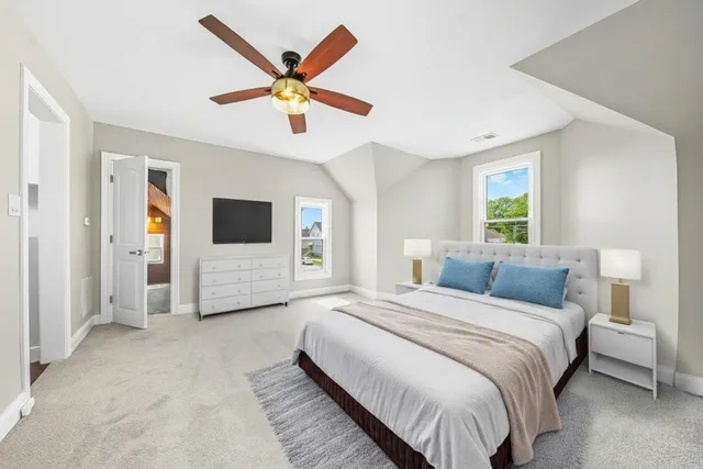 a bedroom with a large bed a ceiling fan and a balcony