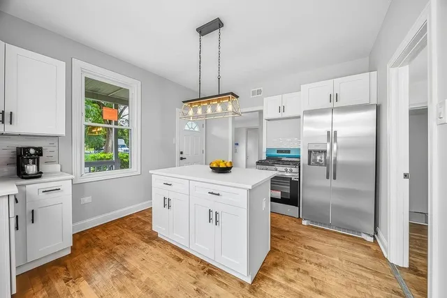 a kitchen with stainless steel appliances granite countertop a refrigerator a sink dishwasher a oven with white cabinets and wooden floor