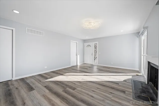 an empty room with wooden floor and fireplace