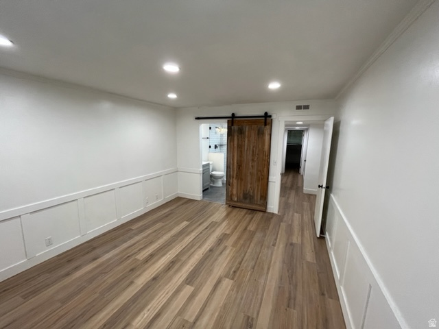 6884 670 East Midvale, UT 84047 - Photo 10 of 28 Spare room with a barn door, a decorative wall, dark wood finished floors, wainscoting, and recessed lighting