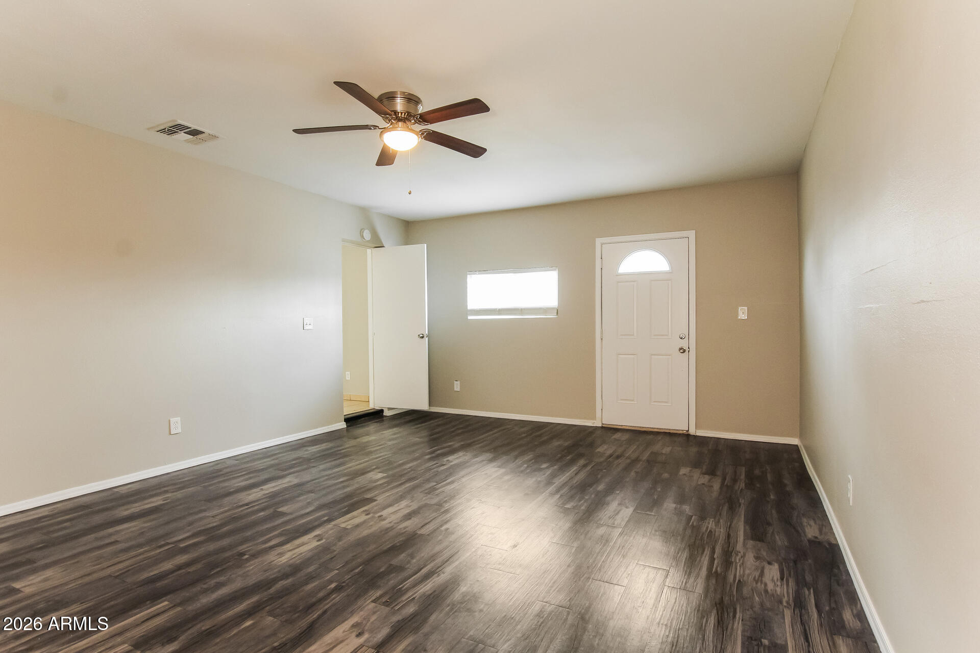 3650 West Berridge Lane Phoenix, AZ 85019 - Photo 7 of 21 an empty room with wooden floor fan and windows